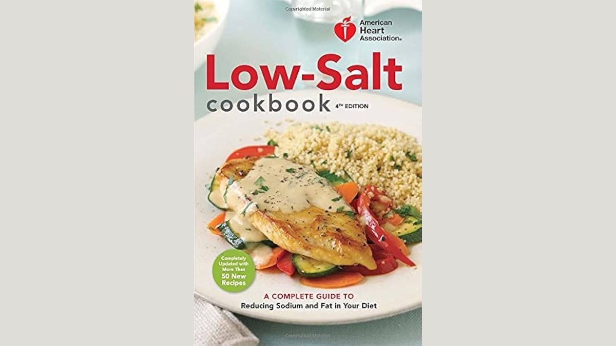 A collection of heart-healthy nutrition books displayed alongside fresh vegetables on a kitchen counter.