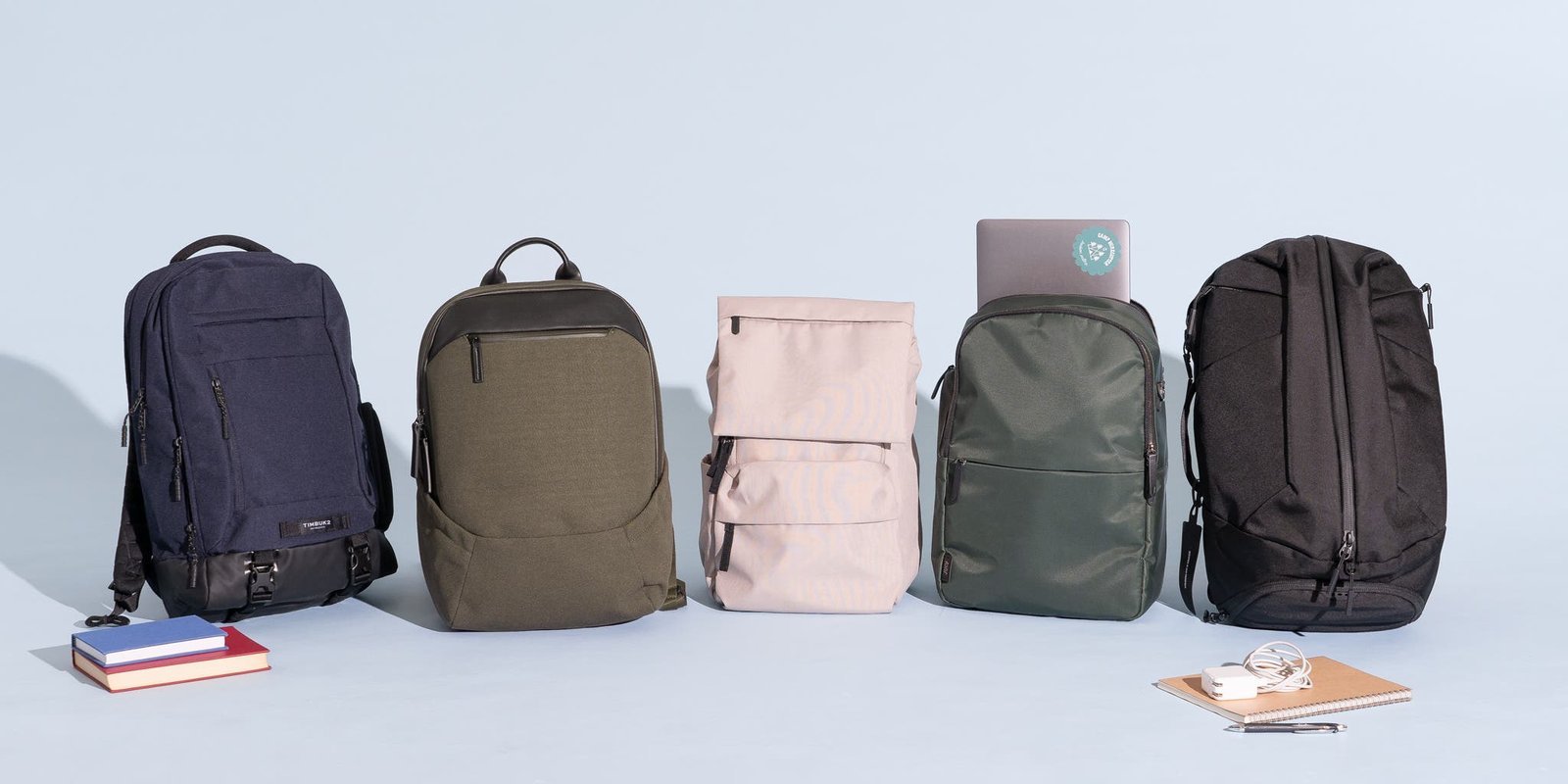 A modern travel and work backpack sitting in a bright, sunlit airport terminal.