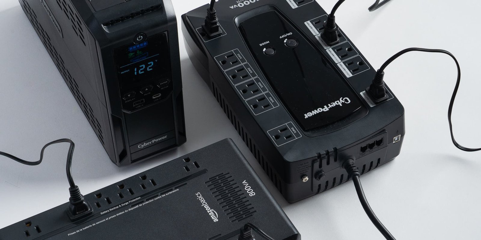 A modern uninterruptible power supply unit sits on a desk next to a computer.