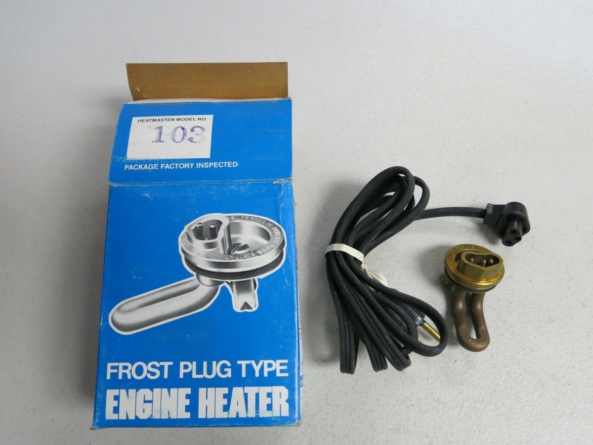 A brass freeze plug engine heater installed in a car engine block.