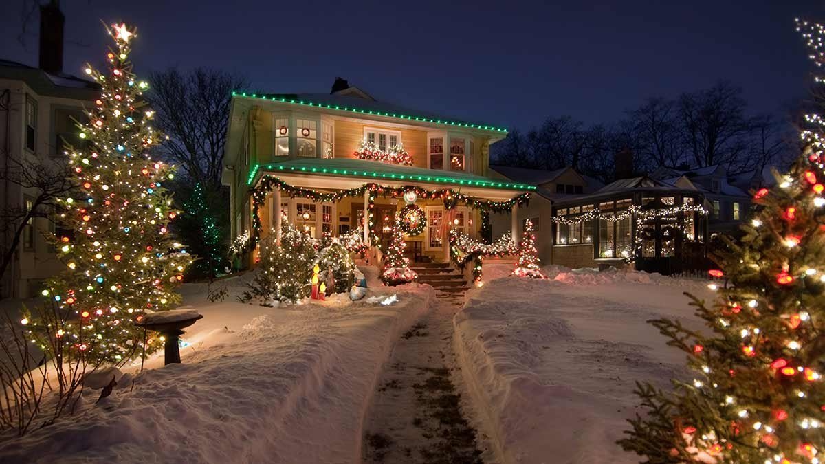 A smart outdoor timer controls festive Christmas lights on a suburban porch at dusk.