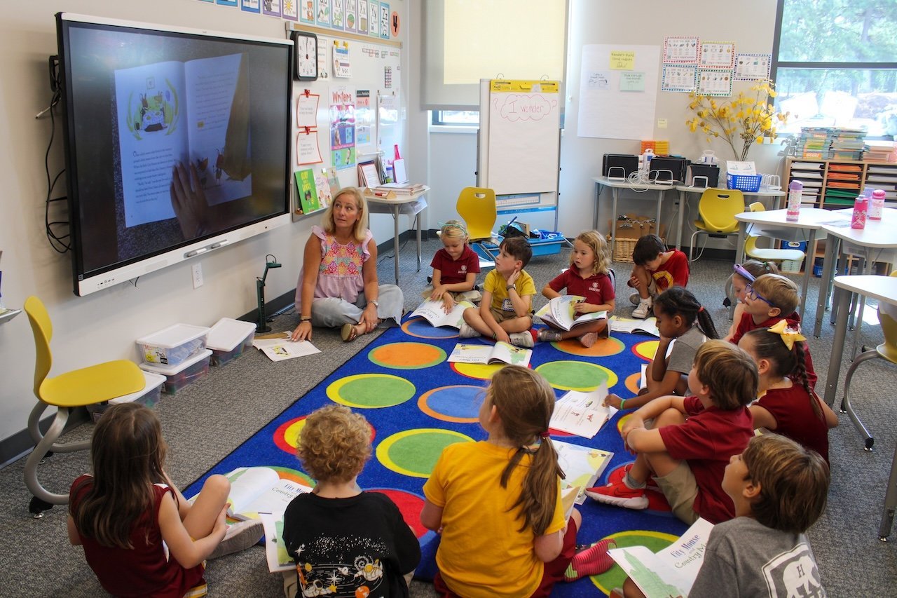 A collection of engaging phonics teaching materials and books displayed on a wooden desk.