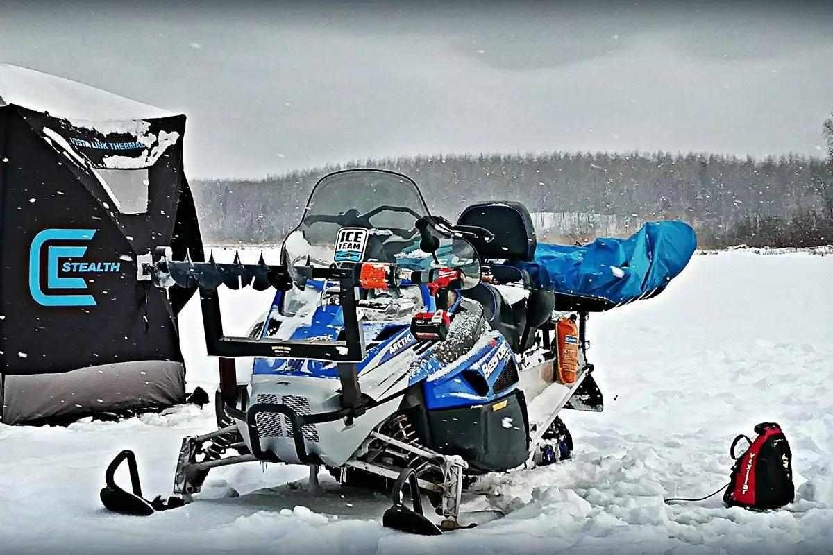 A rugged snow machine parked on a frozen lake for ice fishing.