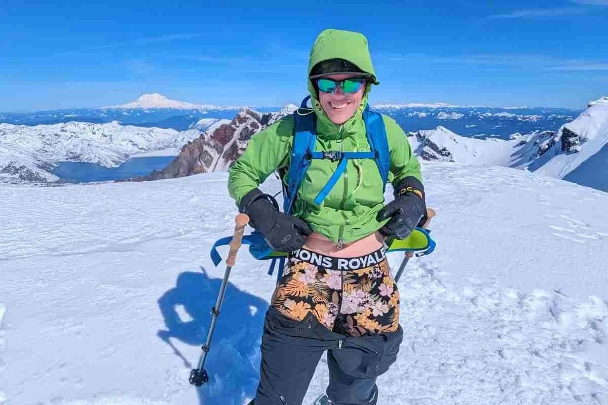 A woman wearing comfortable thermal underwear bottoms standing in a sunlit winter cabin.