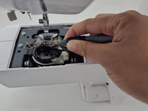 Cleaning lint from the bobbin race of a Brother sewing machine.