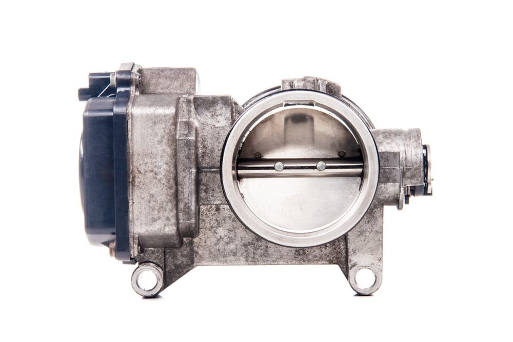 A dirty idle air control valve held by a mechanic for inspection.
