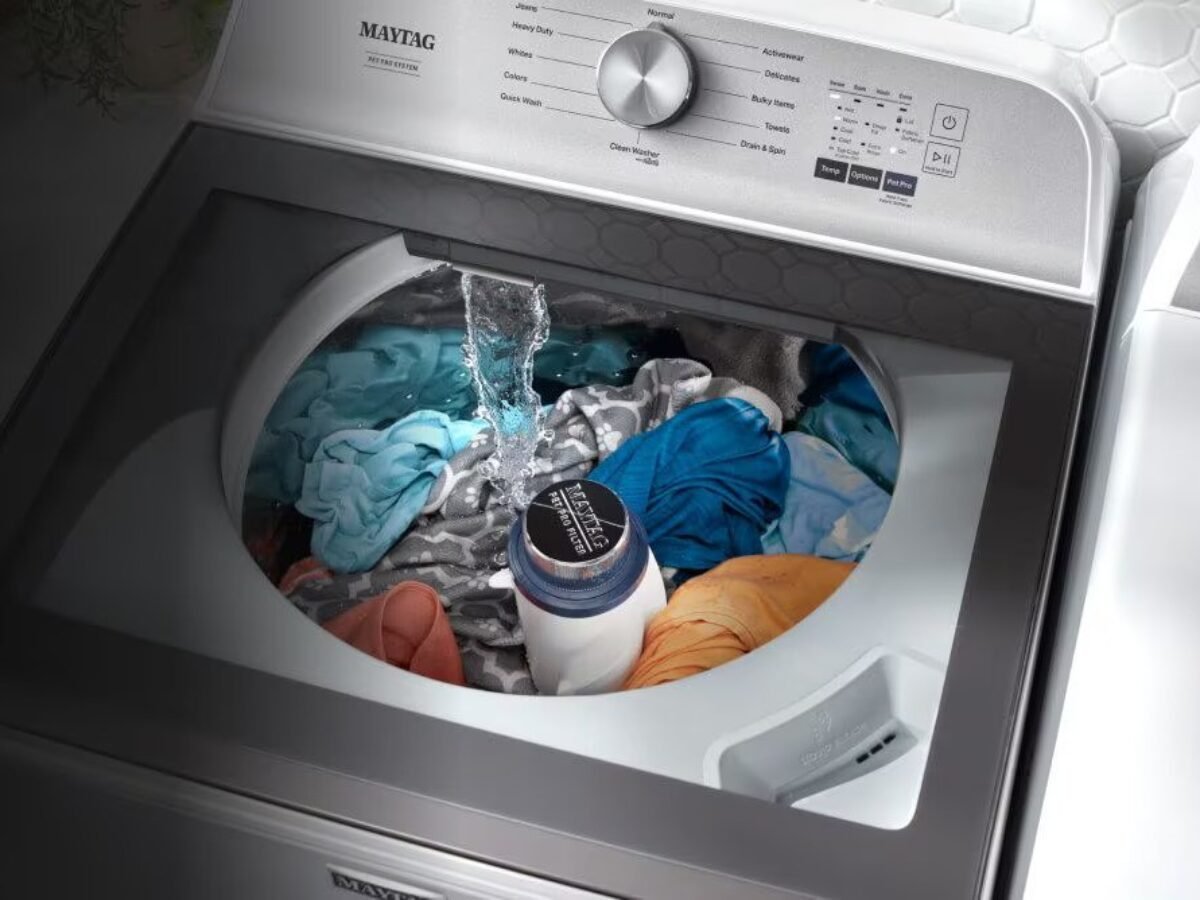 Heavy wet laundry sitting in a basket next to a modern washing machine.