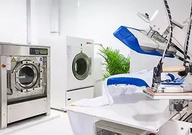 A hand reaches to toggle the power switch on a commercial laundry machine.