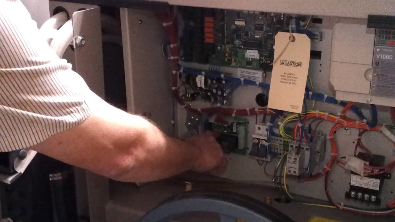Close-up of a red emergency stop button on a Milnor washing machine panel.