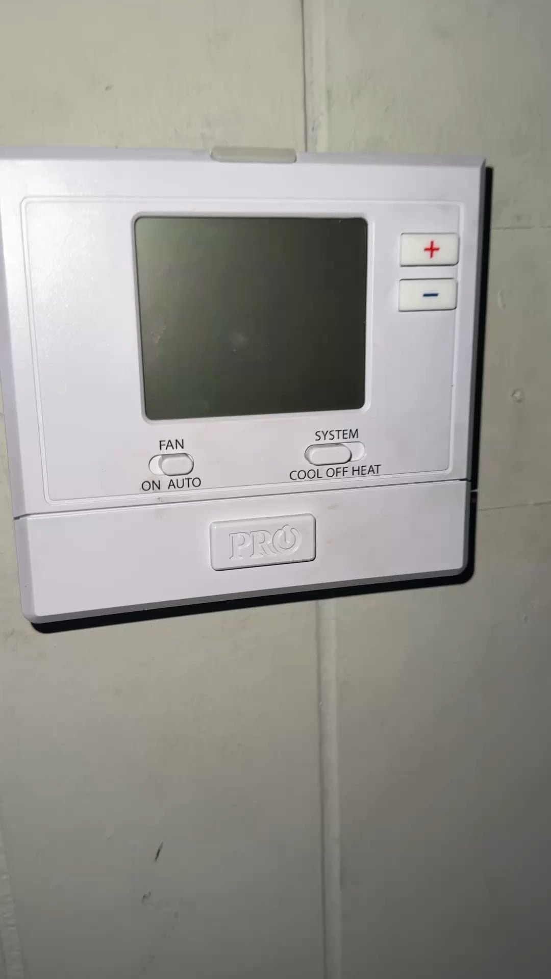Inspecting and securing loose electrical wires on the back of a thermostat.
