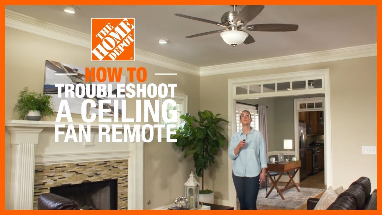 A person reaching toward a ceiling fan to re-pair the handheld control.