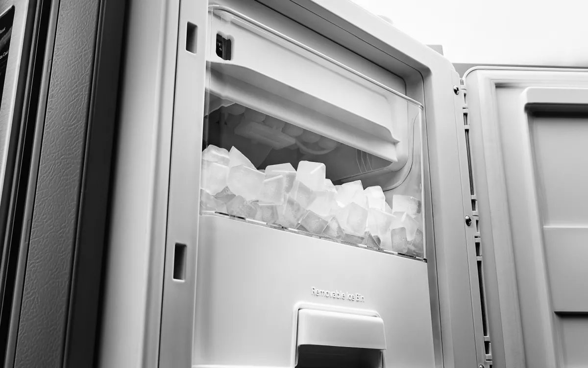A technician checking the water supply line connection for a refrigerator ice maker.