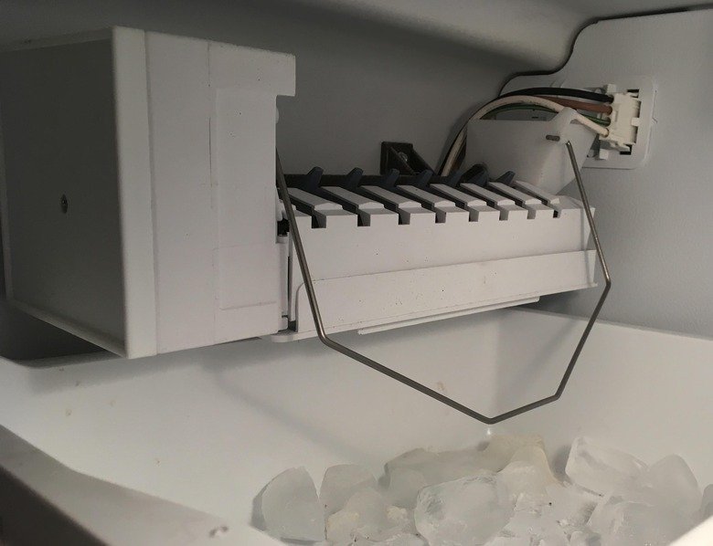 An open modern freezer drawer featuring the internal refrigerator ice maker mechanism.