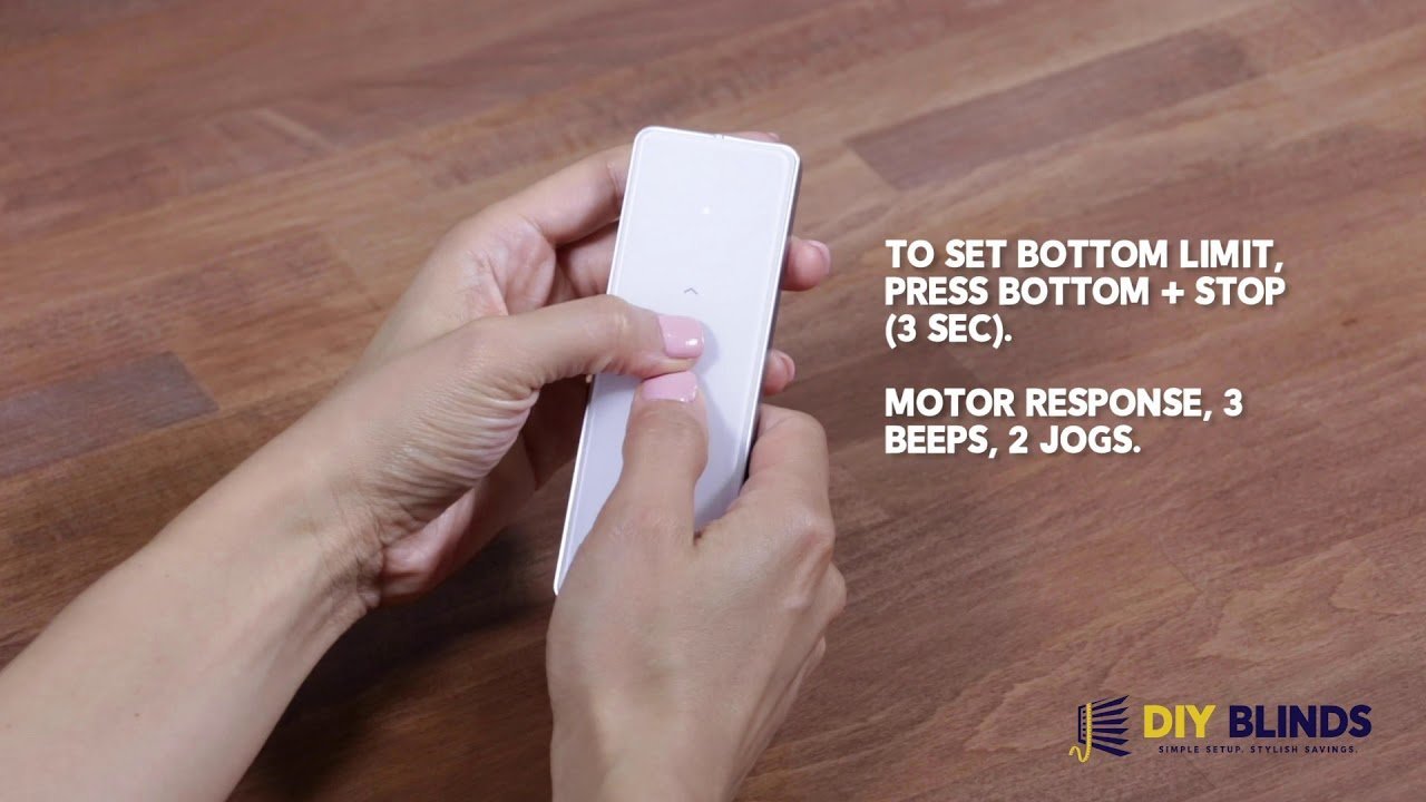 A modern wireless remote control for motorized blinds sitting on a minimalist side table.