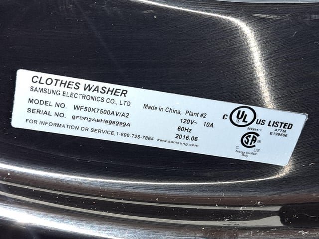 A person using a bubble level to ensure the washing machine is level.