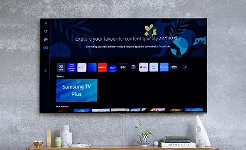 A modern Samsung smart TV mounted on a living room wall in natural light.