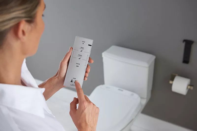 A modern electronic bidet toilet seat installed in a bright, clean residential bathroom.