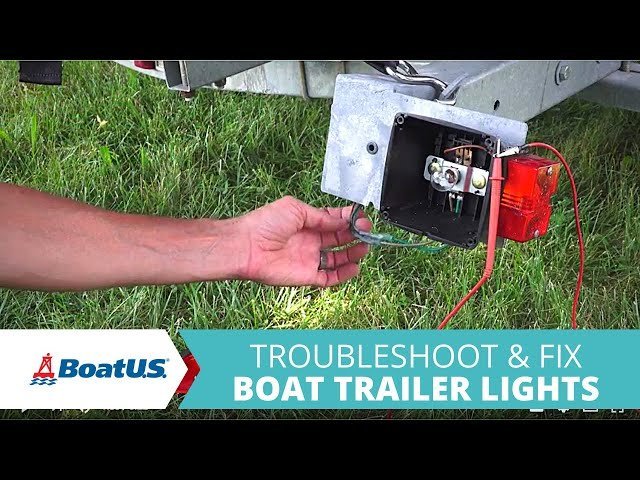 Mechanic inspecting a trailer tail light bulb and socket for potential electrical faults.