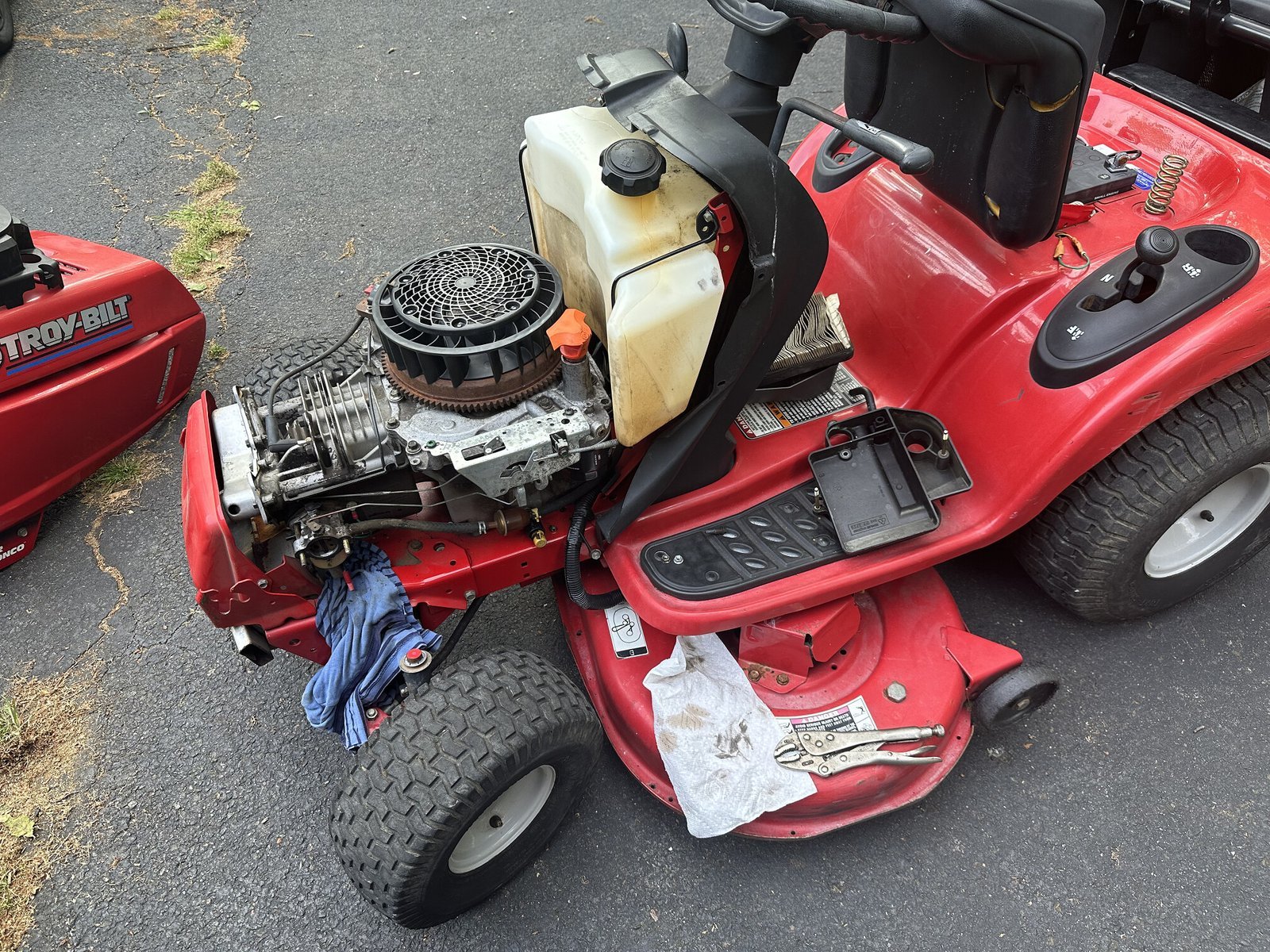 Mechanic inspecting the engine and fuel system of a riding mower for troubleshooting.
