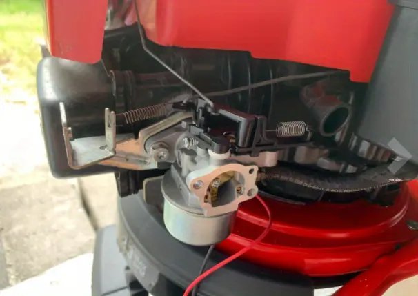 Fuel stabilizer sitting on a workbench next to a gas can for mower maintenance.