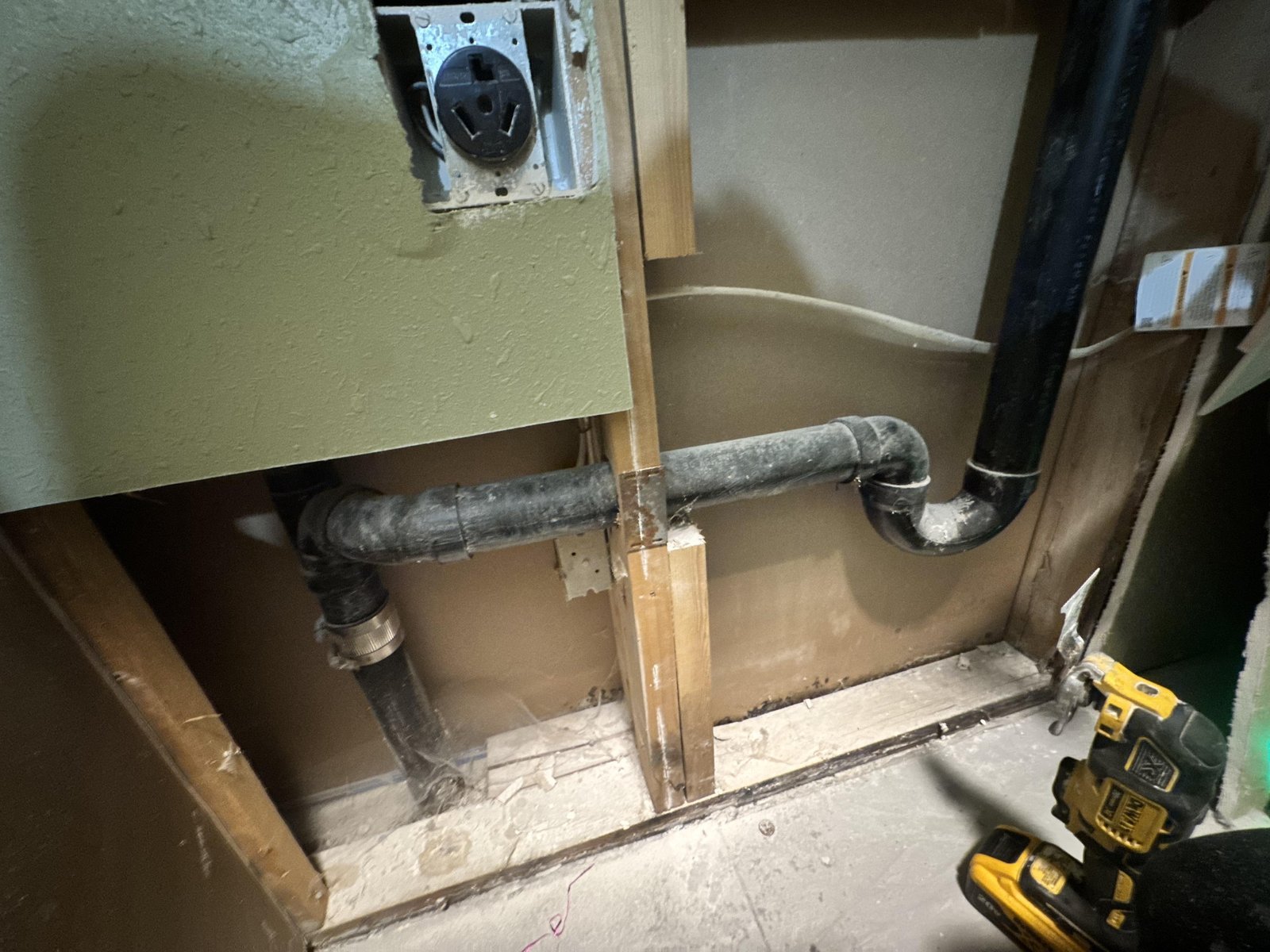 Clogged washing machine drain hose showing debris buildup inside the wall standpipe.