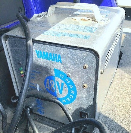 Diagnostic tools arranged next to a Yamaha 48 volt charger for troubleshooting.