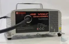 A Yamaha 48 volt charger connected to a golf cart in a garage.